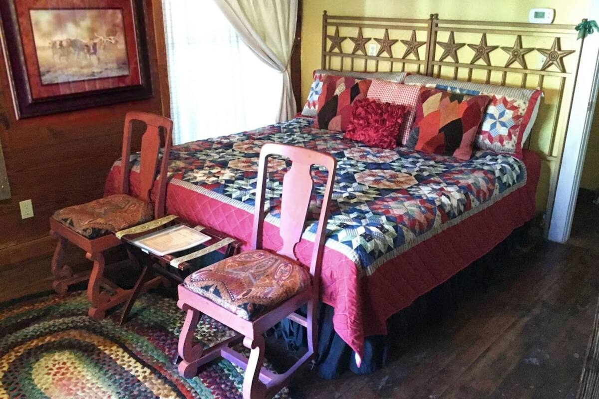 A bedroom with a bed, a chair, a rug, and a wall-mounted clock.