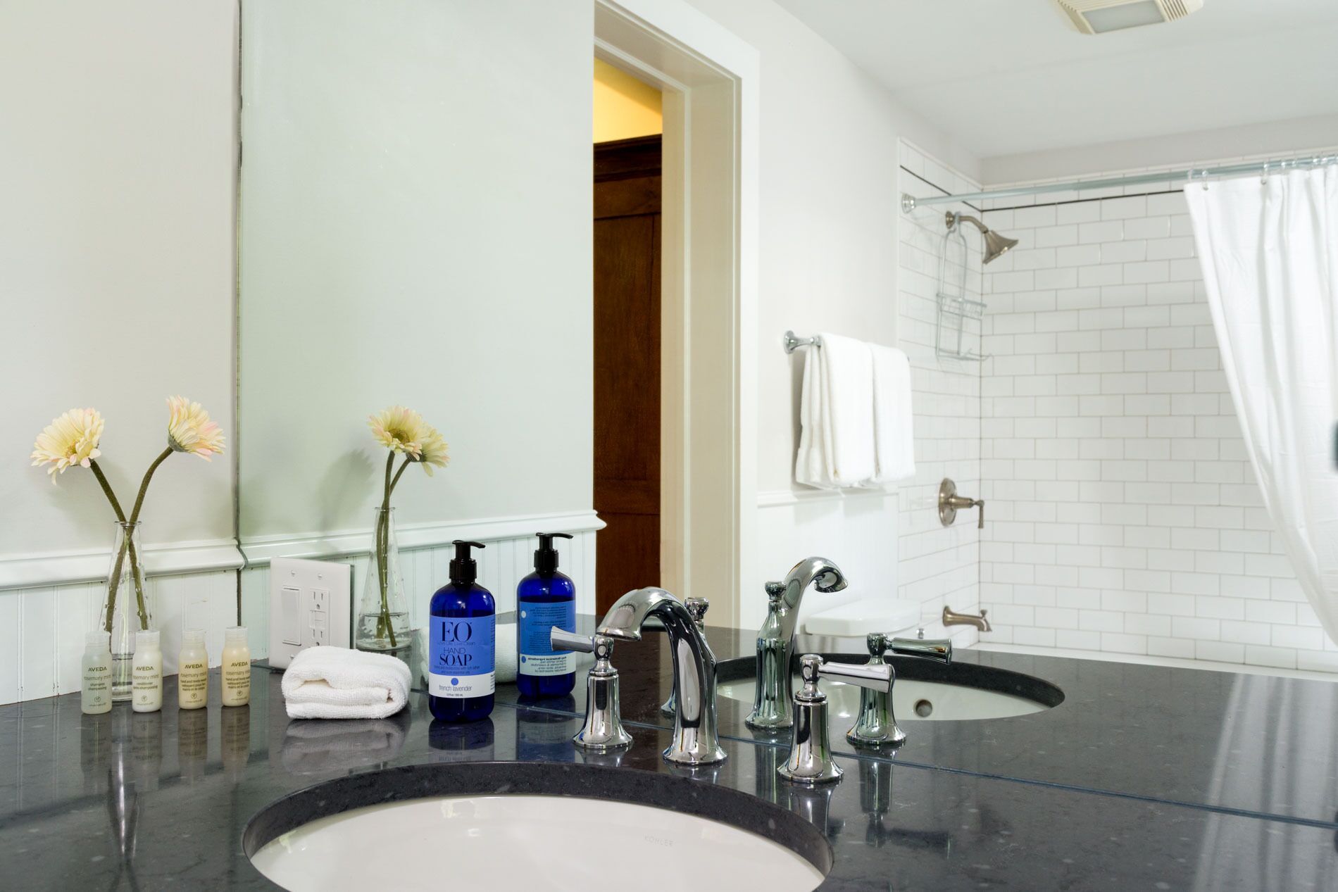 A bathroom with two sinks, a large mirror, and a shower area.