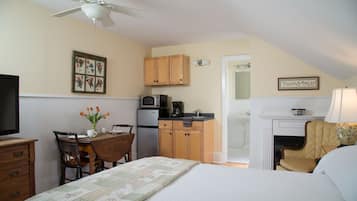 Una habitación compacta con cama, una mesa de comedor con sillas, una kitchenette y una chimenea.