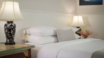 A hotel room with a bed, two bedside lamps, a vase with flowers, and a painting on the wall.