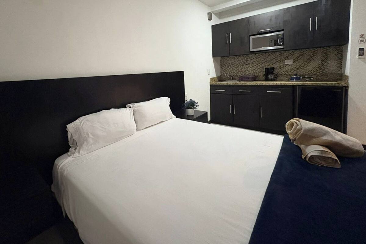 Una habitación de hotel con una cama, un cabecero oscuro, un microondas y una cafetera en la encimera.