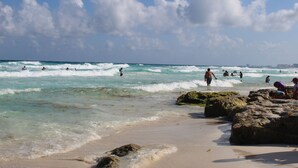 A beach with clear skies, waves, and people swimming and walking along the shore. - Casa Balam Cancun (Cancun)