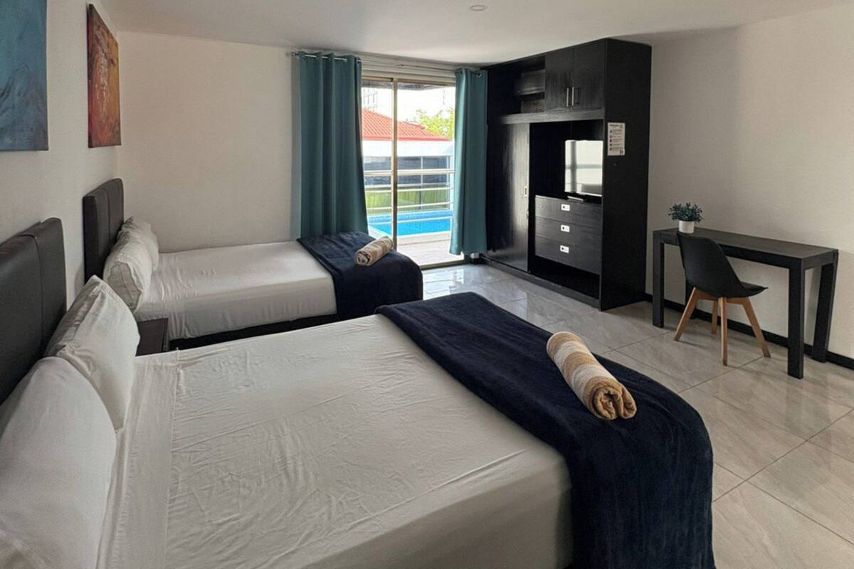 Una habitación de hotel con dos camas, un escritorio y vista a la piscina.