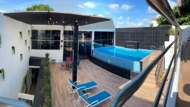A modern outdoor pool area with a covered seating area and lounge chairs. - Casa Balam Cancun (Cancun)