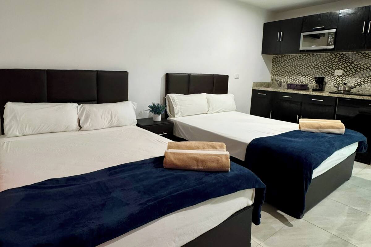 Habitación de hotel con dos camas, un kitchenette y piso de baldosas.