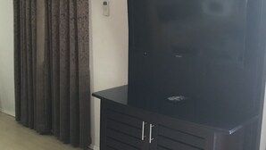 Una habitación con un mueble multimedia negro grande, techo de madera y ventana con cortinas.