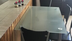Un salón de conferencias con una mesa de vidrio, paneles de madera y sillas negras.