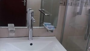 A bathroom with a white sink, a mirror, a glass shower enclosure, and a cabinet with drawers. - Two Bedroom House HHK-17-2 (Lautoka)