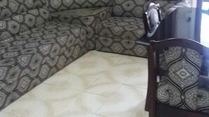 Un salon d’angle avec un canapé à motifs, une chaise en bois et un sol carrelé.