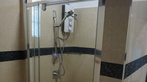 A glass-enclosed shower stall with a handheld showerhead and a wall-mounted faucet. - One Bedroom House HHK-19-1 (Lautoka)