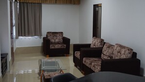 A living room with a sofa set, a glass coffee table, and a door leading to another room. - One Bedroom House HHK-19-1 (Lautoka)