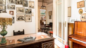 Una habitación con una mesa de comedor, sillas, una araña y una pared decorada con numerosas fotografías enmarcadas.