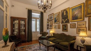 Un salón tradicional con un sofá, sillones, una mesa de centro y una araña.