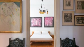 Un dormitorio con cama de madera, lámpara colgante y cuadros en las paredes.