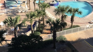 Un hotel con varios balcones, piscina y palmeras.