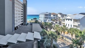Un hotel frente a la playa con varias edificaciones, una zona de piscina con sillas de descanso y vista al océano.