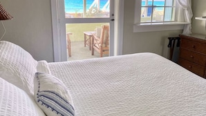 Un dormitorio con cama, cómoda de madera y ventana con vista a la playa.