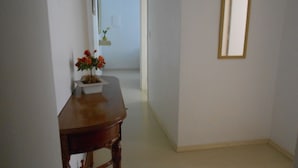 A hallway with a wooden table and a potted plant. - Relaxation and comfort on the beach - Gonzaguinha (São Vicente)