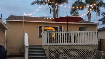 A house with a balcony, a red umbrella, and string lights.