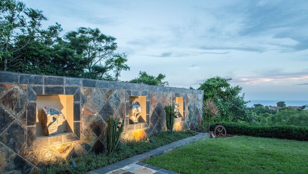 Un muro de piedra con iluminación empotrada y plantas de cactus.