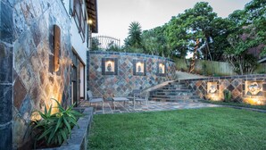 Un patio de paredes de piedra con mobiliario exterior y una pequeña escalera que sube a un nivel superior.