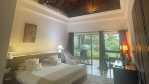 Une chambre spacieuse avec un grand lit, un bureau et une vue sur l’extérieur grâce à une porte-fenêtre coulissante.
