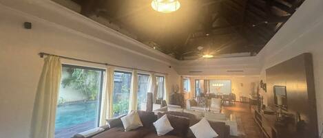 A spacious living room with a large sectional sofa, a dining area, and a view of a swimming pool.