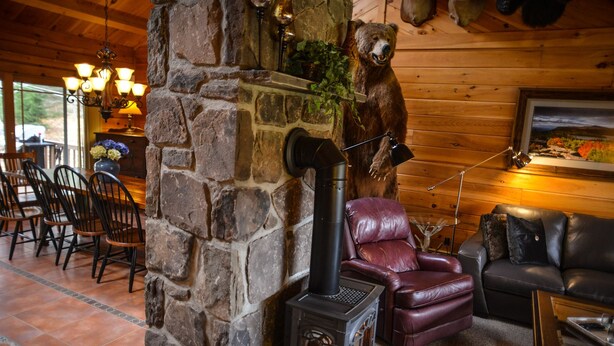 Een gezellig cabin interieur met een stenen openhaard, leren zitmeubels en een beren decoratie.