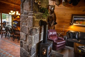 A cozy cabin interior with a stone fireplace, leather seating, and a bear decoration. - STUNNING LOG HOME Colgate Lake!!!! Kayaks & SUP Included! Very Private!  (East Jewett)