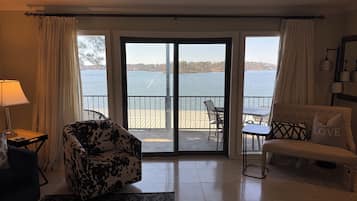 A living room with a view of a lake, a sofa, a chair, and a lamp.