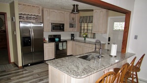 A kitchen with a stainless steel refrigerator, microwave, and oven, a granite countertop, wooden chairs, and a window with curtains. - Book for Winter and Spring!  Great rates! Family and dog friendly! (Lake Harmony)