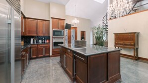 A spacious kitchen with wooden cabinets, stainless steel appliances, a marble countertop island, and a chandelier. - Exquisite house with loft . Great deals for longer stays (Houston)