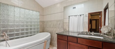 A modern bathroom with a freestanding bathtub, a vanity with a mirror, and a glass shower enclosure.