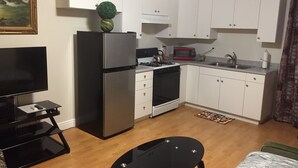 A compact kitchen with white cabinets, a refrigerator, a microwave, and a stove.