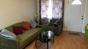 A living room with a green sofa, a round coffee table, and a green armchair.