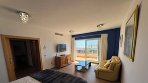 A hotel room with a bed, a sofa, a TV, a desk, and a balcony with a view. - Detached Villa with Private Pool, close to all amenities and a blue flag beach (Santiago del Teide)