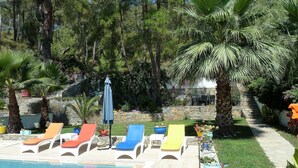 A pool area with lounge chairs and a stone wall.