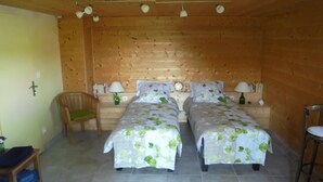 Une chambre avec deux lits, des murs en bois, une chaise et une petite table.