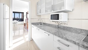 A modern kitchen with white cabinets, a granite countertop, a built-in microwave, and a stainless steel sink.
