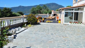 A stone-paved patio with outdoor furniture, a white balustrade, and a view of a mountain and sea. - Vacation rental in the Gulf of Valinco A PROPRIANO -South Corsica (Propriano)