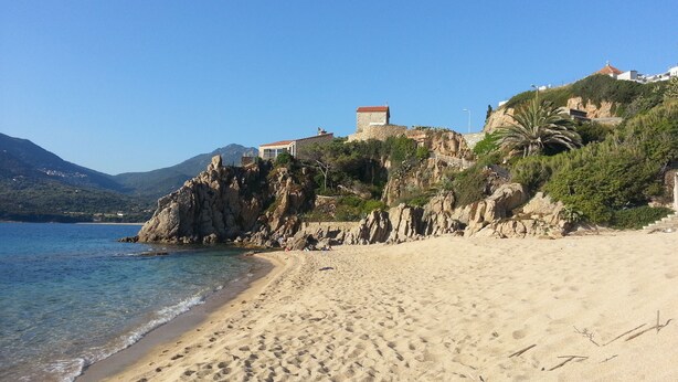 A beach with clear blue water, sandy shore, rocky cliffs, and buildings on the hillside. - Vacation rental in the Gulf of Valinco A PROPRIANO -South Corsica (Propriano)