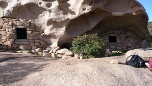 A stone structure with two small openings, a bush in front, and a backpack on the ground. - Vacation rental in the Gulf of Valinco A PROPRIANO -South Corsica (Propriano)