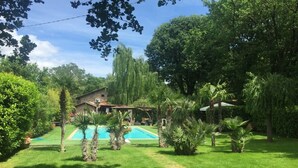A house with a swimming pool surrounded by lush greenery and trees. - Tuscan rustic villa with pool, wifi, outdoor jacuzzi, (Pieve al Toppo)