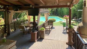 A wooden deck with a pool, outdoor furniture, and a TV screen. - Tuscan rustic villa with pool, wifi, outdoor jacuzzi, (Pieve al Toppo)