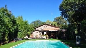 A swimming pool with lounge chairs and a stone building with a tiled roof. - Tuscan rustic villa with pool, wifi, outdoor jacuzzi, (Pieve al Toppo)