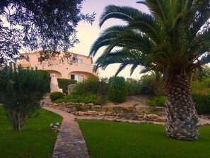 A garden with a stone pathway leading to a building with arches. - Villa in peaceful location, superb views, pool, garden, mini golf and ping pong (Picota)