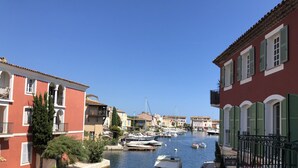 A canal with boats docked, surrounded by buildings with balconies and shutters. - Fully renovated air-conditioned cabin close to the beach (Port Grimaud)
