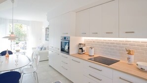 A modern kitchen with white cabinetry, a wooden countertop, and a built-in oven. - Fully renovated air-conditioned cabin close to the beach (Port Grimaud)