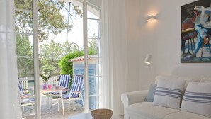 A living room with a white sofa, striped chairs, a small table with a basket, and a painting on the wall. - Fully renovated air-conditioned cabin close to the beach (Port Grimaud)