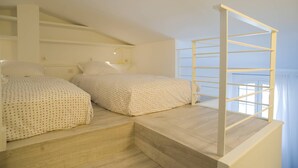 A bedroom with two beds, a wooden staircase, and a window with a view. - Fully renovated air-conditioned cabin close to the beach (Port Grimaud)